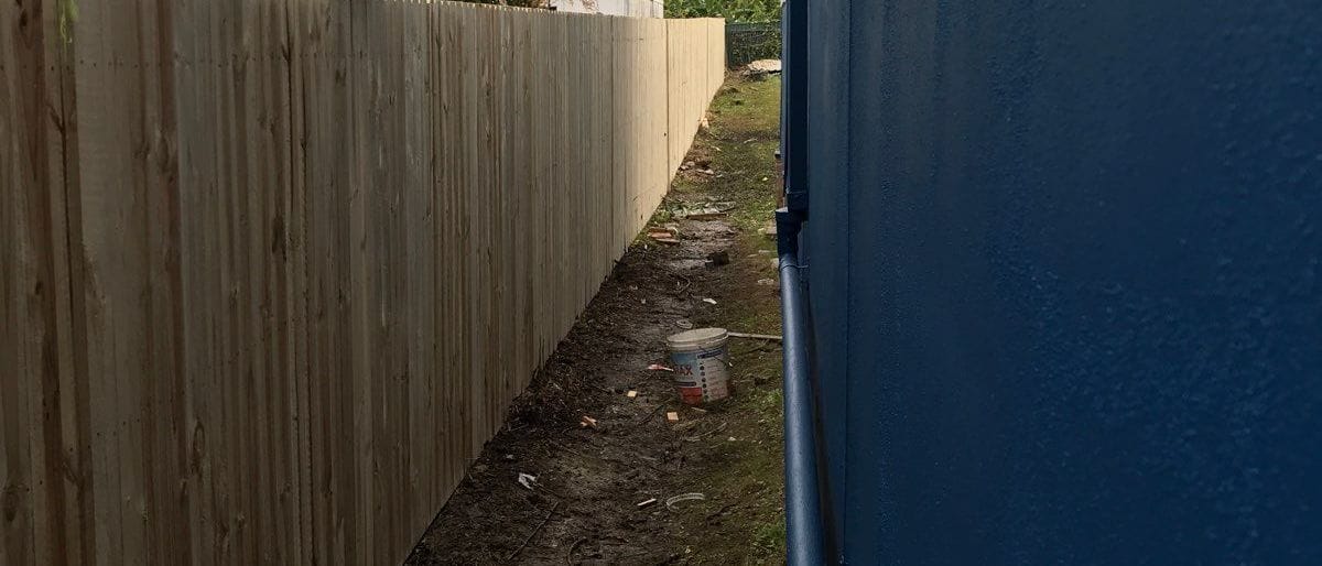 Treated pine timber fence built beside a dark rendered wall along a Sydney side boundary