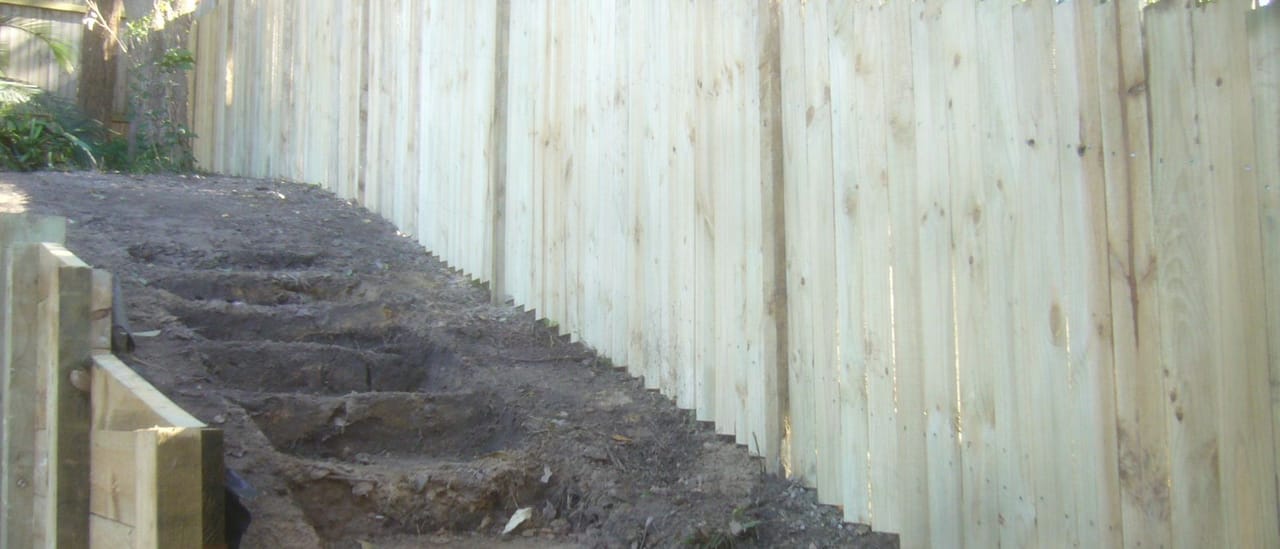Treated pine timber fence stepped down sloping ground alongside excavated steps in Windsor, Sydney